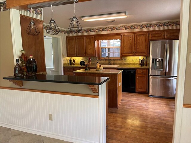 kitchen with sink, black dishwasher, kitchen peninsula, stainless steel fridge, and decorative light fixtures