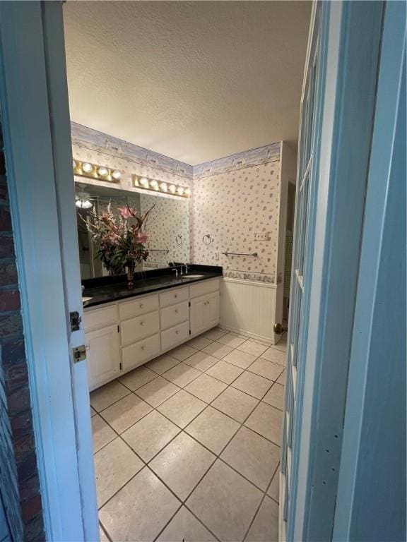 bathroom with tile patterned floors, vanity, and a textured ceiling