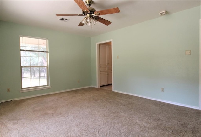 spare room featuring a wealth of natural light, ceiling fan, and light carpet