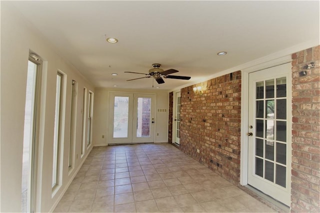 unfurnished sunroom featuring ceiling fan and french doors