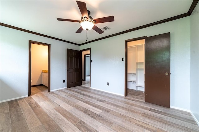 unfurnished bedroom with connected bathroom, ceiling fan, a walk in closet, a closet, and light wood-type flooring