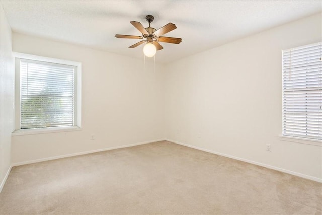 empty room with light carpet, ceiling fan, and baseboards