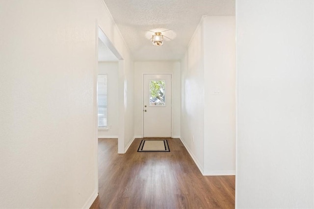 doorway featuring a textured ceiling, wood finished floors, and baseboards