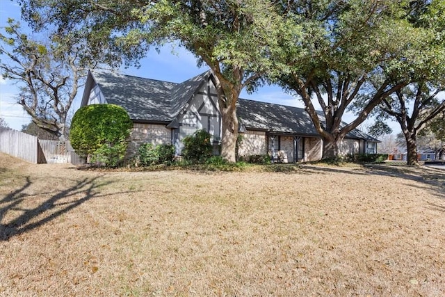 tudor-style house featuring a front yard and fence