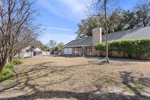 rear view of house with french doors, a chimney, and fence