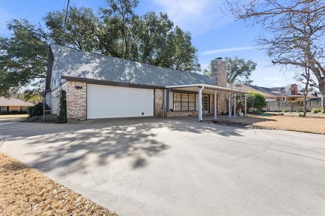 single story home featuring brick siding, a chimney, fence, a garage, and driveway