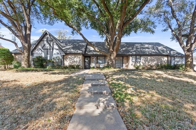 tudor house featuring a front yard and brick siding