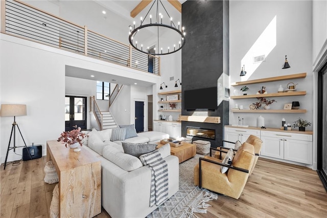 living room with an inviting chandelier, light hardwood / wood-style flooring, built in features, and a high ceiling