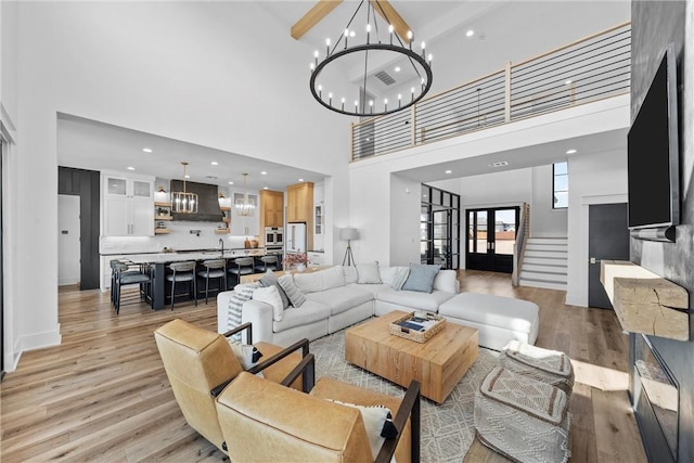 living room with a high ceiling, a chandelier, and light wood-type flooring