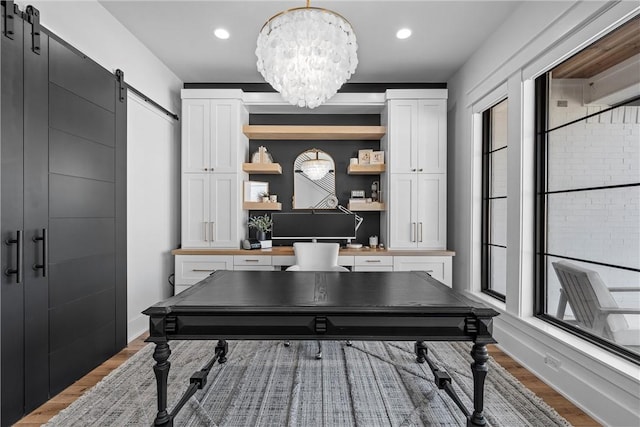 office space featuring an inviting chandelier, hardwood / wood-style floors, and a barn door