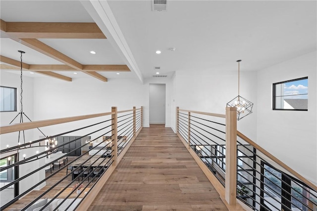 hallway featuring hardwood / wood-style flooring, beam ceiling, and a notable chandelier