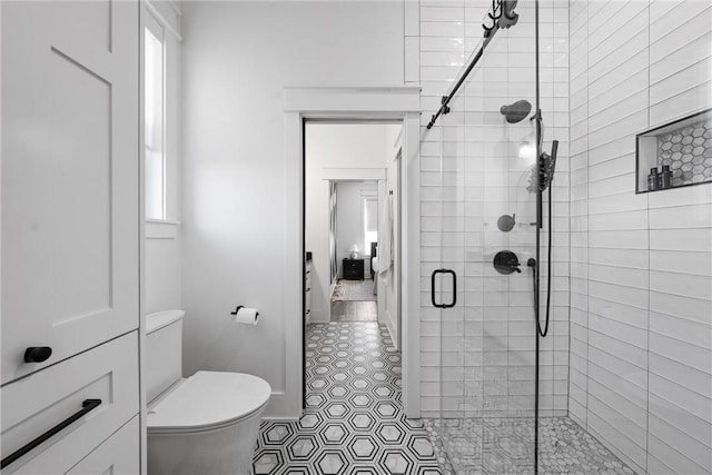 bathroom featuring a healthy amount of sunlight, an enclosed shower, and toilet