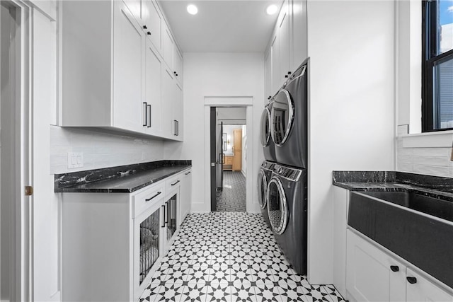 laundry area featuring cabinets, stacked washer and clothes dryer, and sink