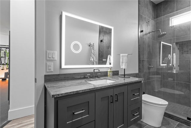 bathroom featuring tiled shower, vanity, and toilet