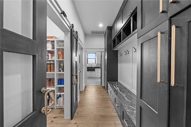 mudroom featuring sink, a barn door, and light wood-type flooring