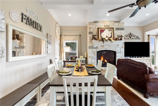 dining space featuring beam ceiling, dark hardwood / wood-style floors, a stone fireplace, and plenty of natural light