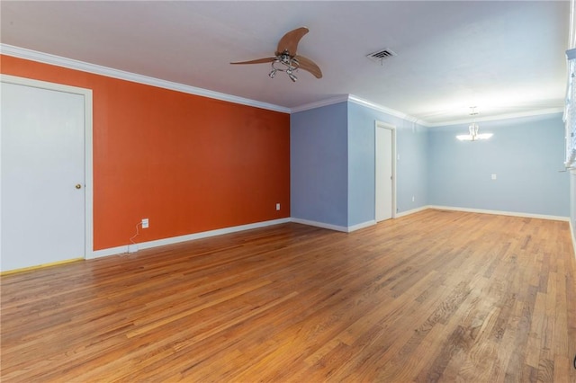 empty room with ceiling fan with notable chandelier, hardwood / wood-style flooring, and crown molding