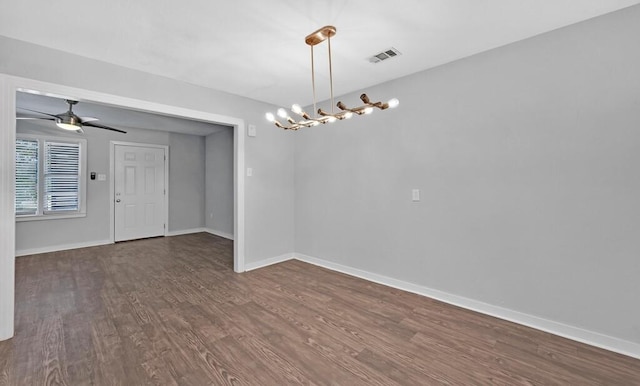 unfurnished room with ceiling fan with notable chandelier and dark hardwood / wood-style floors