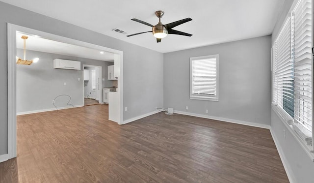 spare room with dark hardwood / wood-style floors, a wall unit AC, and ceiling fan