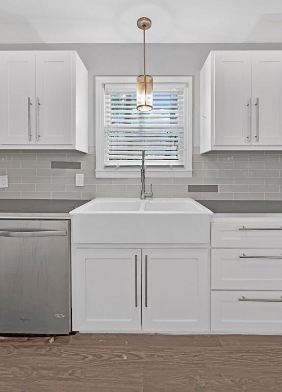 kitchen with tasteful backsplash, white cabinetry, hanging light fixtures, and stainless steel dishwasher