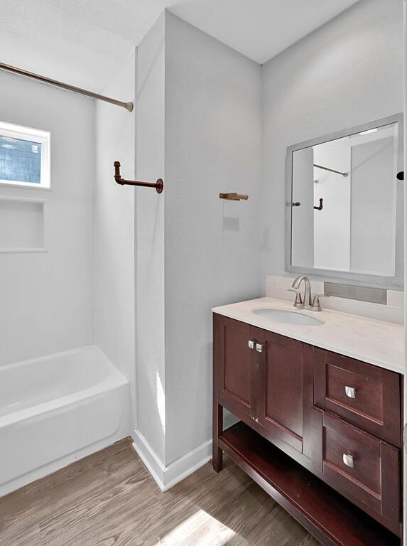 bathroom with hardwood / wood-style floors, vanity, and shower / washtub combination