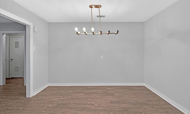 unfurnished dining area featuring dark hardwood / wood-style flooring and a notable chandelier