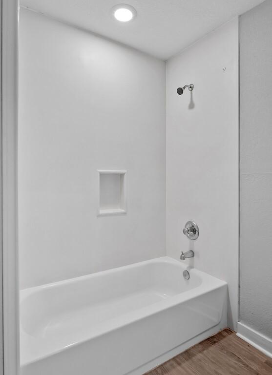 bathroom featuring hardwood / wood-style floors and washtub / shower combination