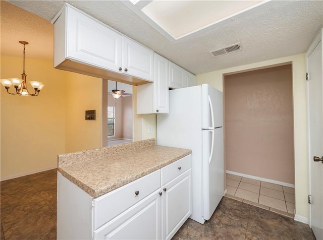 kitchen with white cabinetry, visible vents, freestanding refrigerator, and a textured ceiling