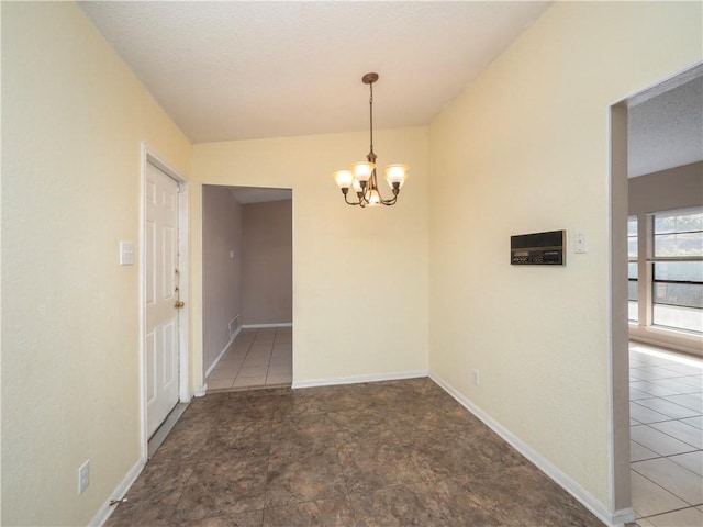 unfurnished room featuring a notable chandelier, baseboards, and a textured ceiling