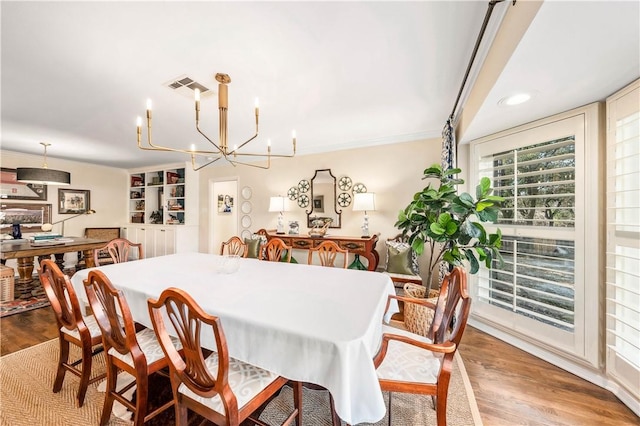 dining area with crown molding, an inviting chandelier, and light hardwood / wood-style floors