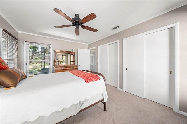 bedroom with multiple closets, light colored carpet, ornamental molding, and ceiling fan