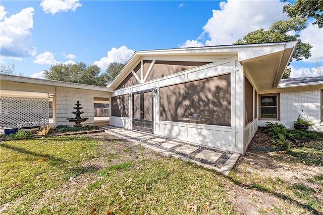 back of house featuring a sunroom and a lawn