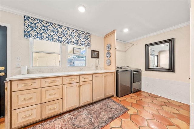 kitchen featuring crown molding, light brown cabinetry, washer and clothes dryer, and sink