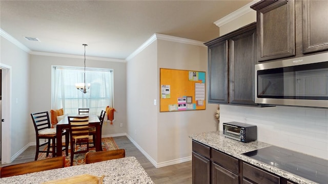 kitchen with pendant lighting, dark brown cabinets, light stone countertops, and black electric cooktop