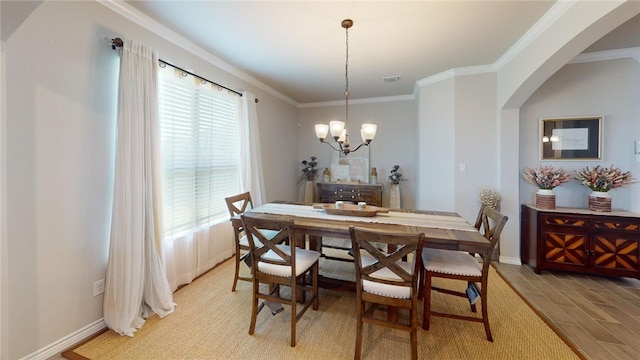 dining space featuring crown molding, light hardwood / wood-style flooring, and a notable chandelier