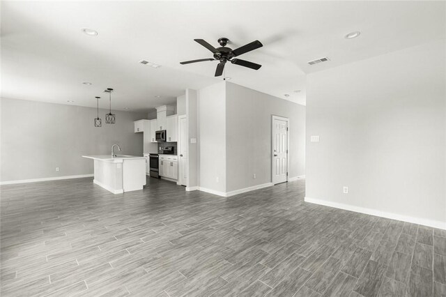 unfurnished living room featuring ceiling fan, light hardwood / wood-style floors, and sink