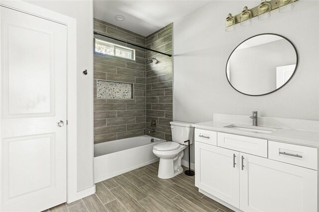 full bathroom featuring vanity, tiled shower / bath combo, and toilet