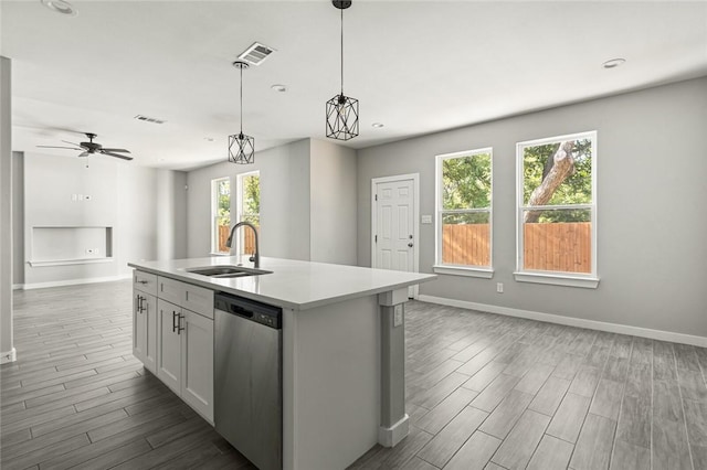 kitchen with dishwasher, a center island with sink, hanging light fixtures, and a healthy amount of sunlight