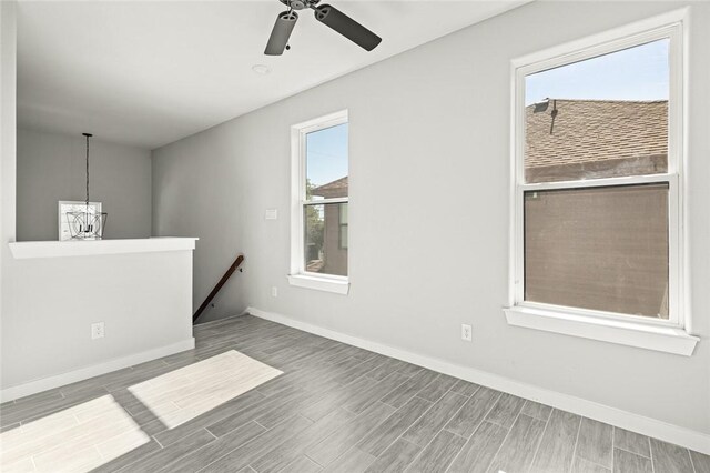 spare room featuring hardwood / wood-style floors and ceiling fan with notable chandelier