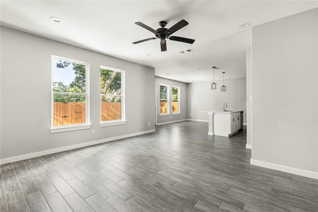 unfurnished living room with ceiling fan, dark hardwood / wood-style flooring, and sink