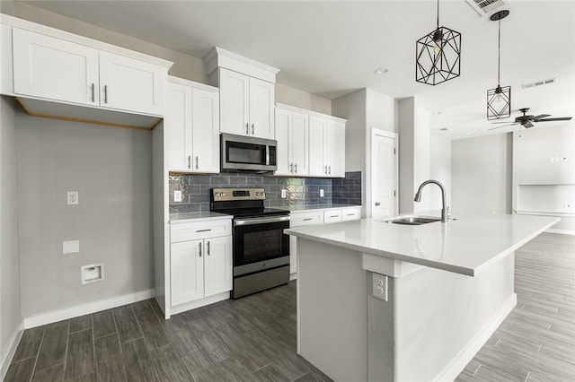 kitchen featuring pendant lighting, sink, an island with sink, appliances with stainless steel finishes, and white cabinetry