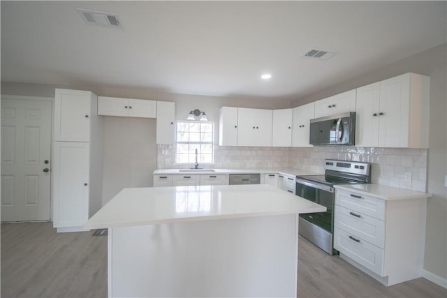 kitchen featuring stainless steel appliances, a sink, visible vents, and white cabinetry