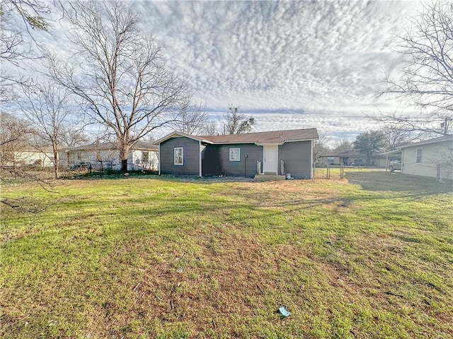 back of property featuring a lawn and fence