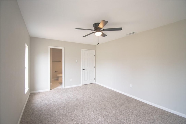 unfurnished bedroom with ensuite bathroom, a ceiling fan, visible vents, baseboards, and carpet