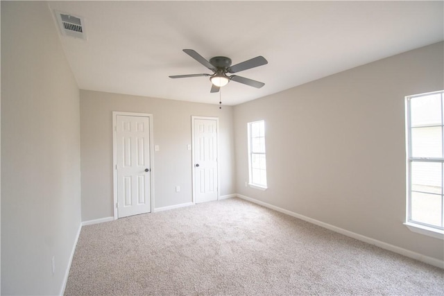 carpeted empty room featuring baseboards, visible vents, and ceiling fan