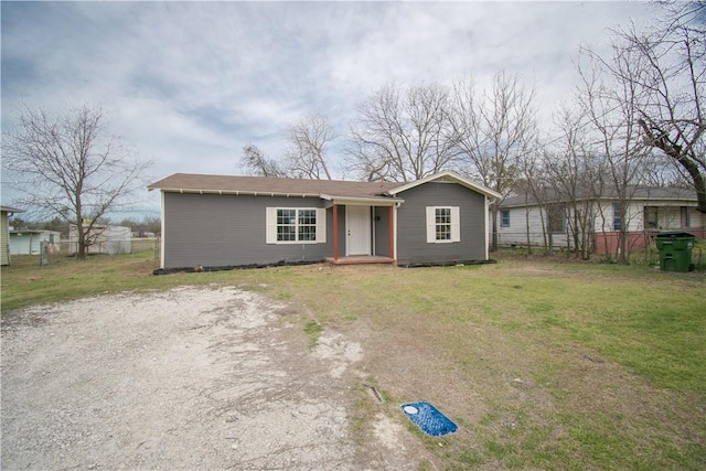 view of front facade featuring driveway, a front lawn, and fence