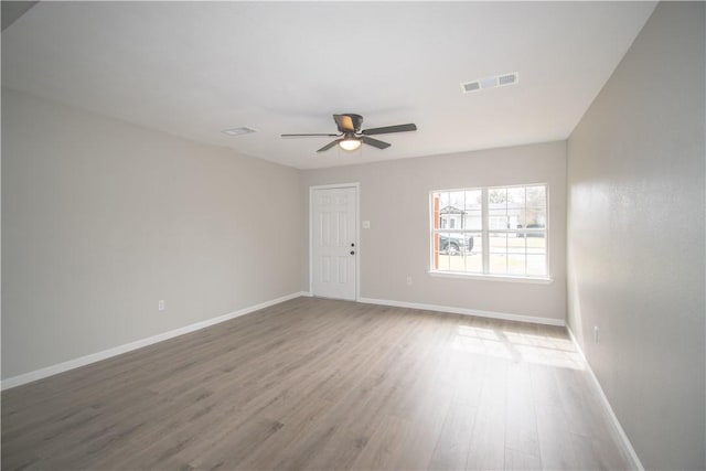 spare room featuring visible vents, ceiling fan, baseboards, and wood finished floors