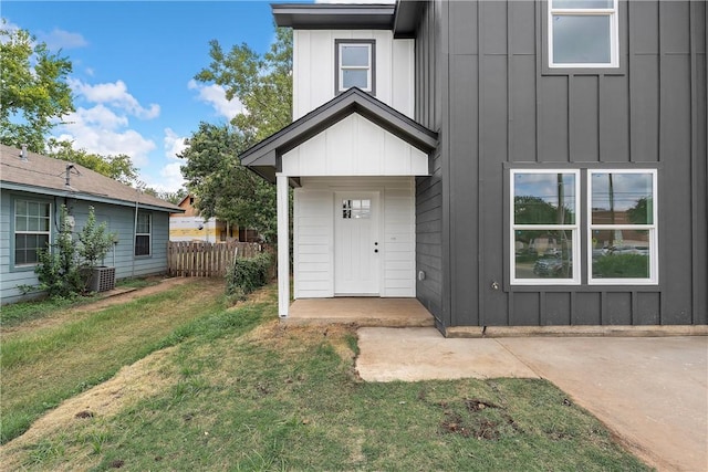 entrance to property featuring a yard and central AC unit