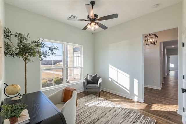 sitting room with wood-type flooring and ceiling fan with notable chandelier