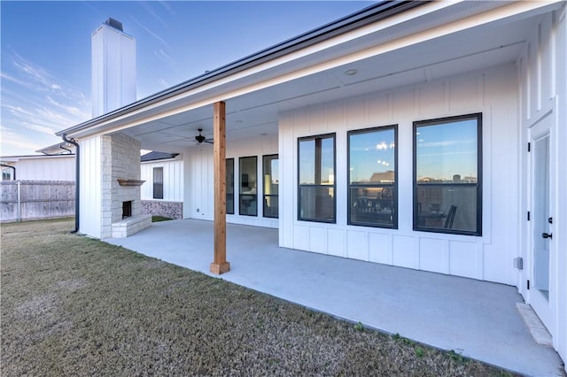 back of property featuring ceiling fan, an outdoor fireplace, a patio area, and a yard